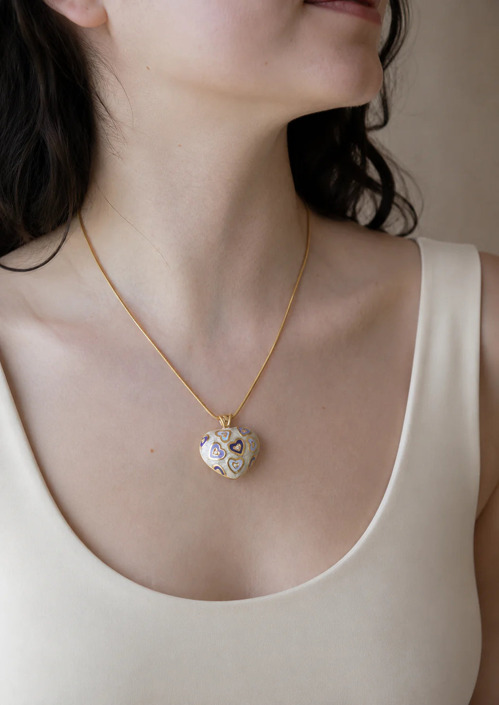 Necklace with a heart-shaped pendant worn by a person in a white tank top.