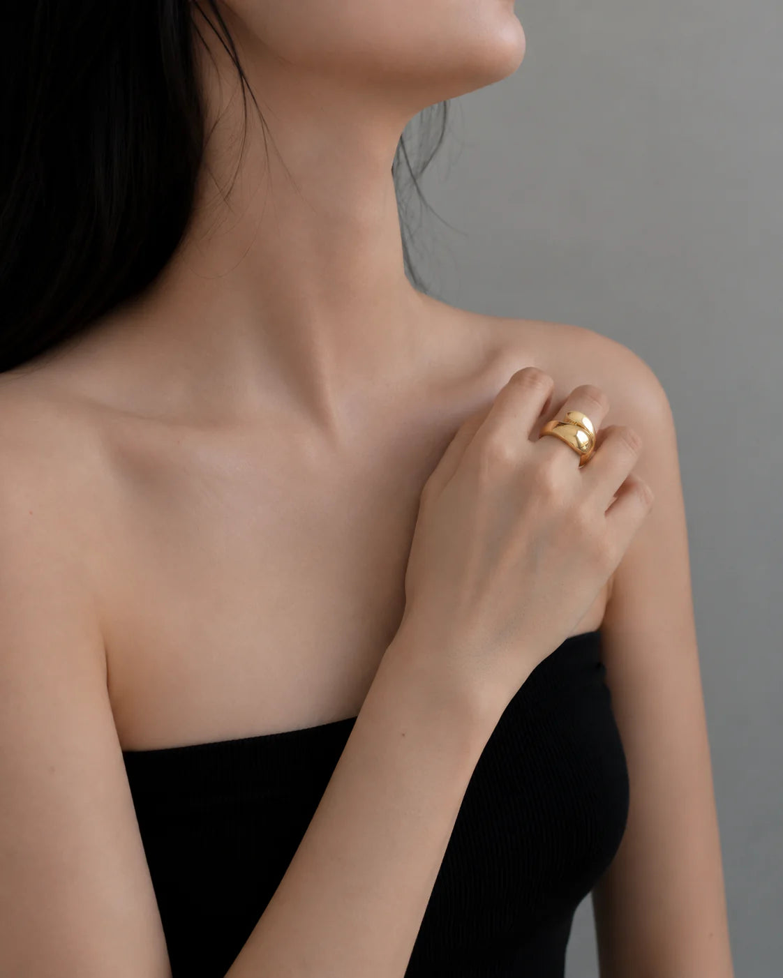 Woman wearing a gold ring on a neutral background