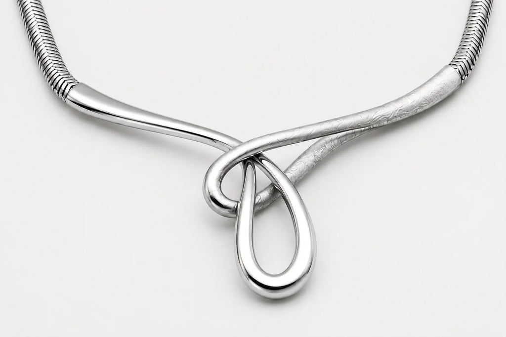 Silver necklace with a teardrop pendant on a light gray background