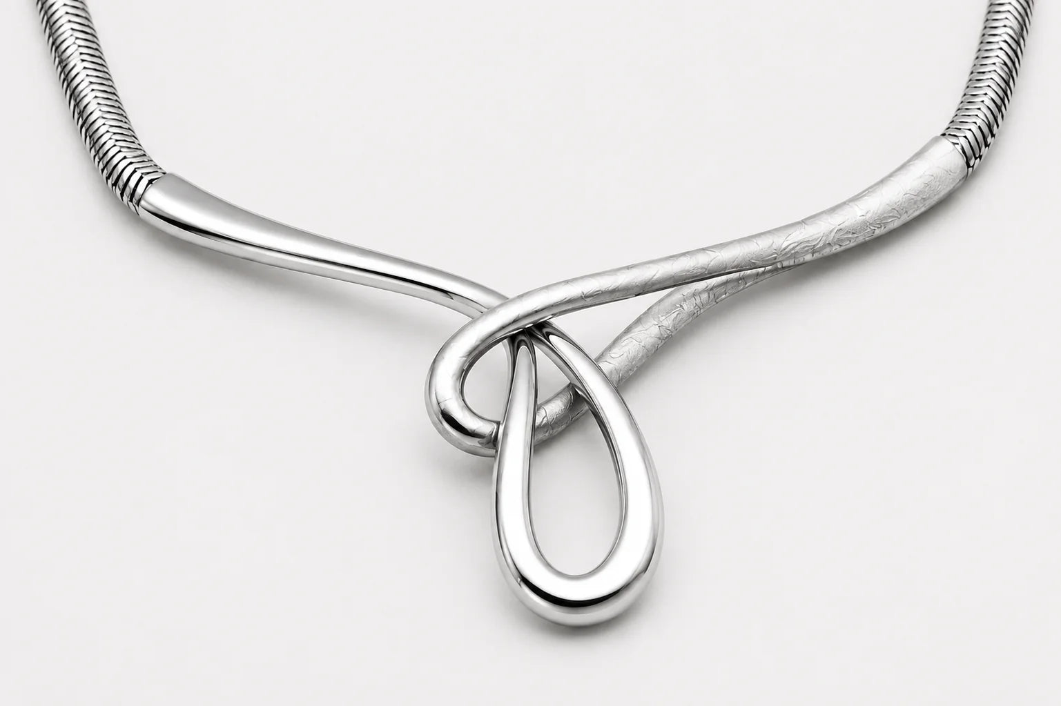 Silver necklace with a teardrop pendant on a light gray background