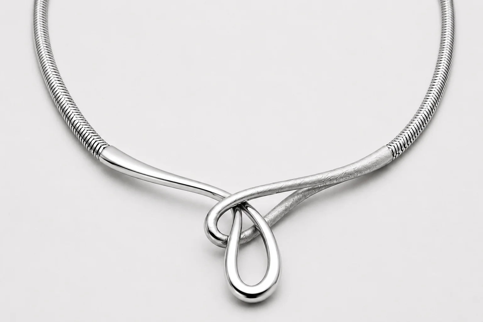 Silver necklace with a teardrop pendant on a light gray background