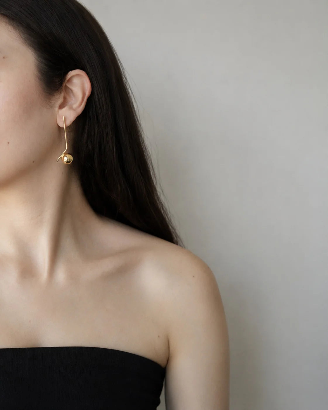 Woman wearing gold hoop earrings against a plain background