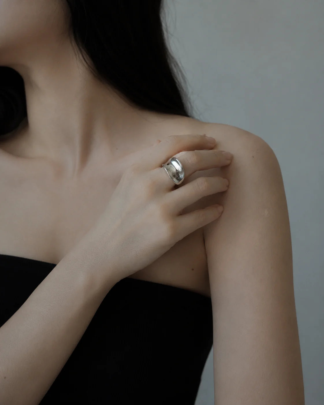 Person wearing a silver ring on a neutral background