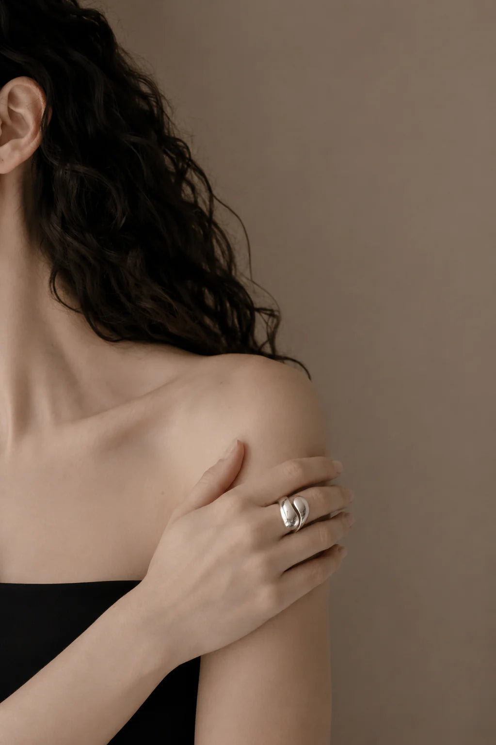 Woman wearing a silver ring on her hand against a neutral background