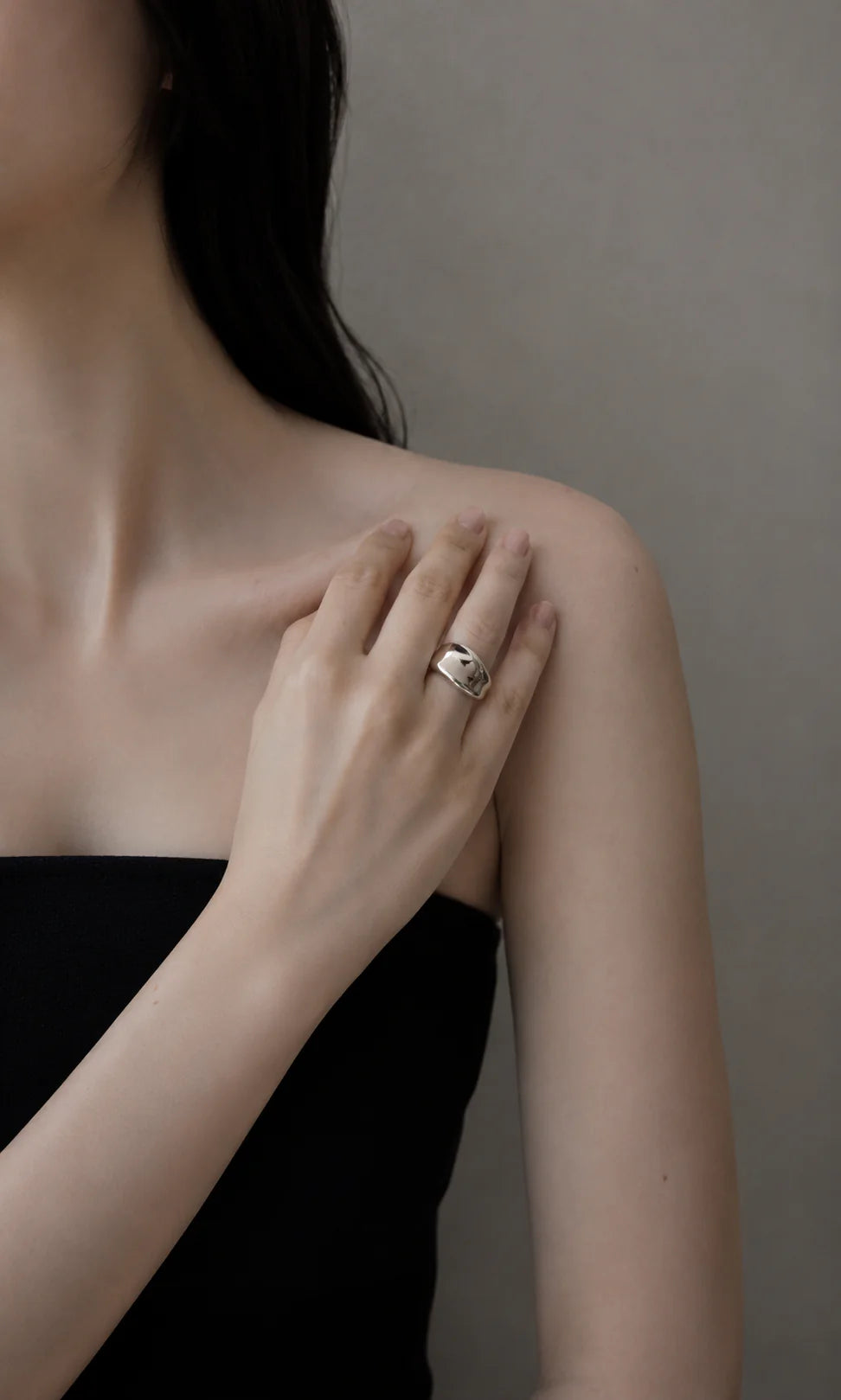 Close-up of a person wearing a ring on a neutral background
