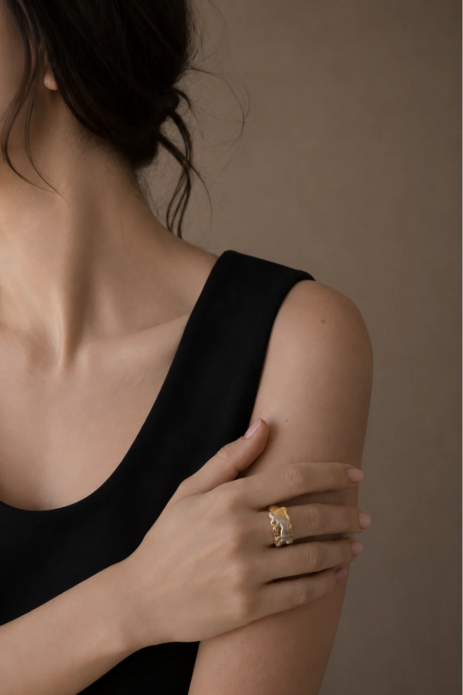 Woman wearing a gold ring on her hand against a neutral background