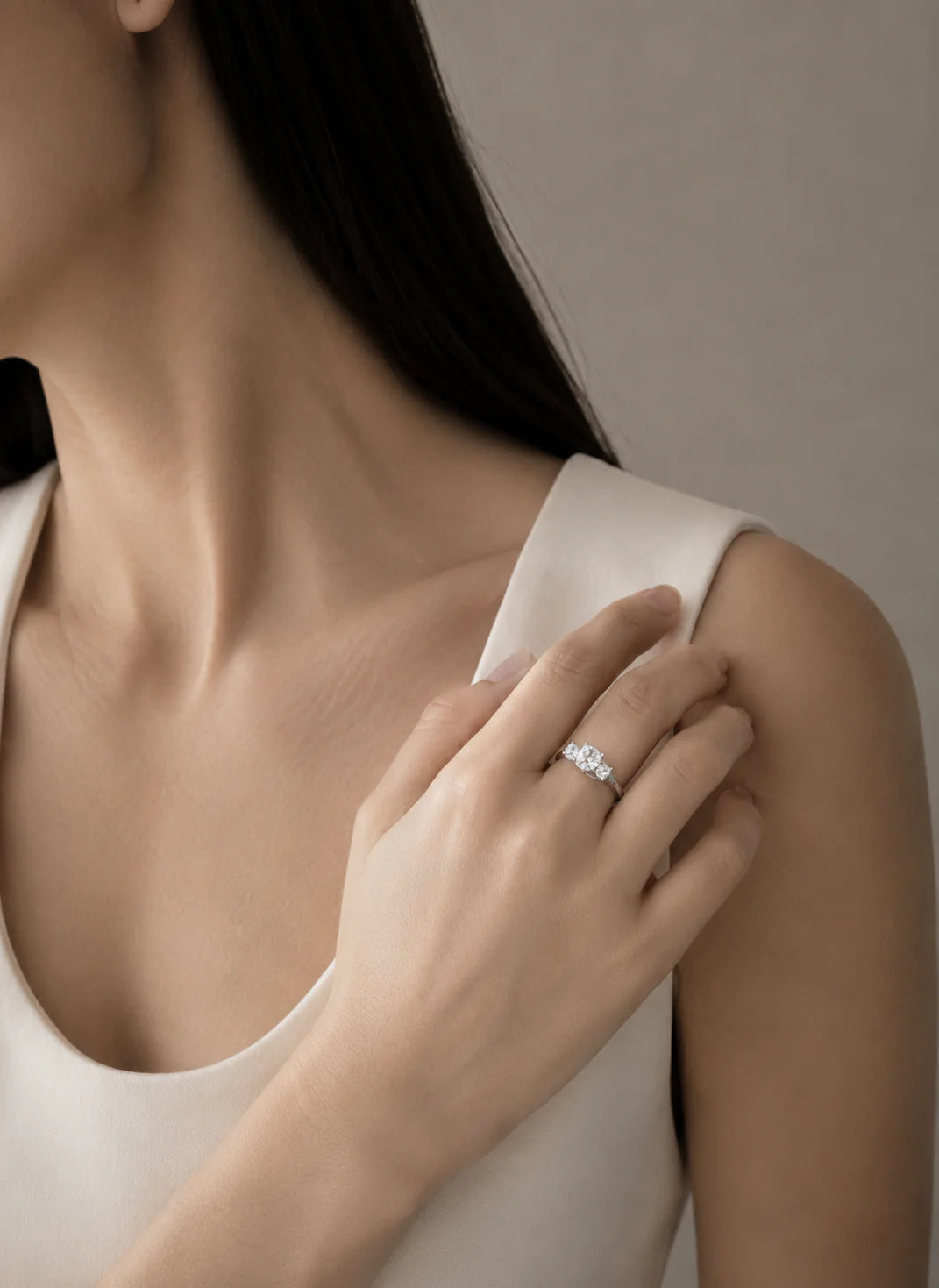 Close-up of a person wearing a diamond ring on a neutral background