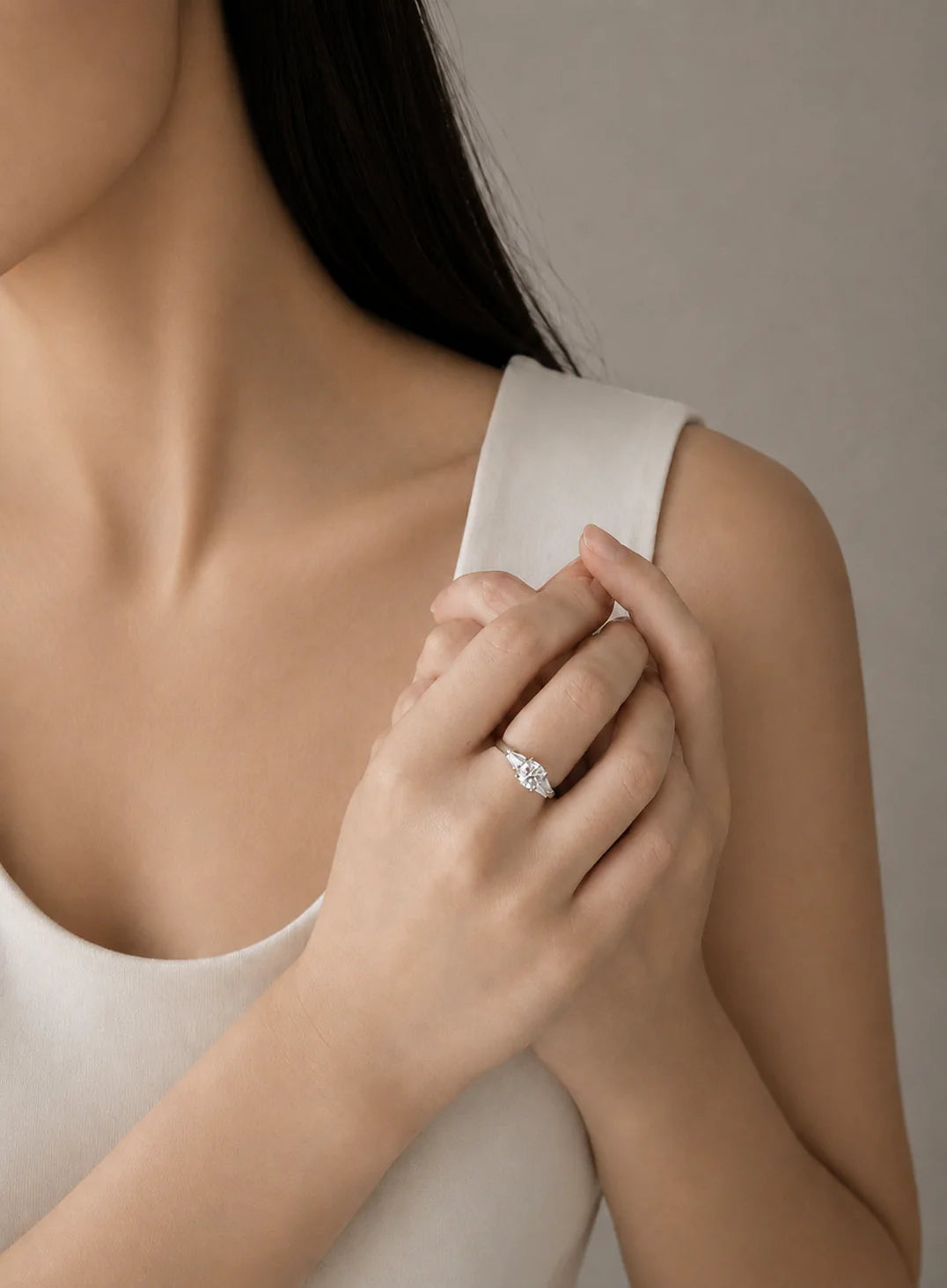 Close-up of a person wearing a baguette dimaond ring on a neutral background