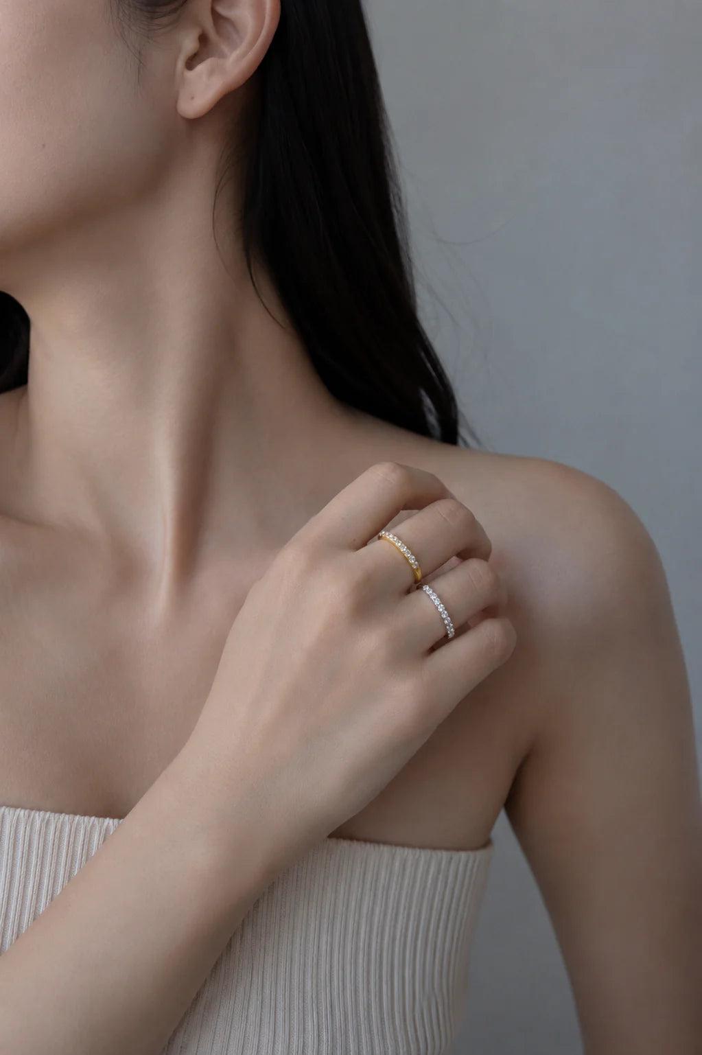 Close-up of a person wearing two rings on their finger against a neutral background