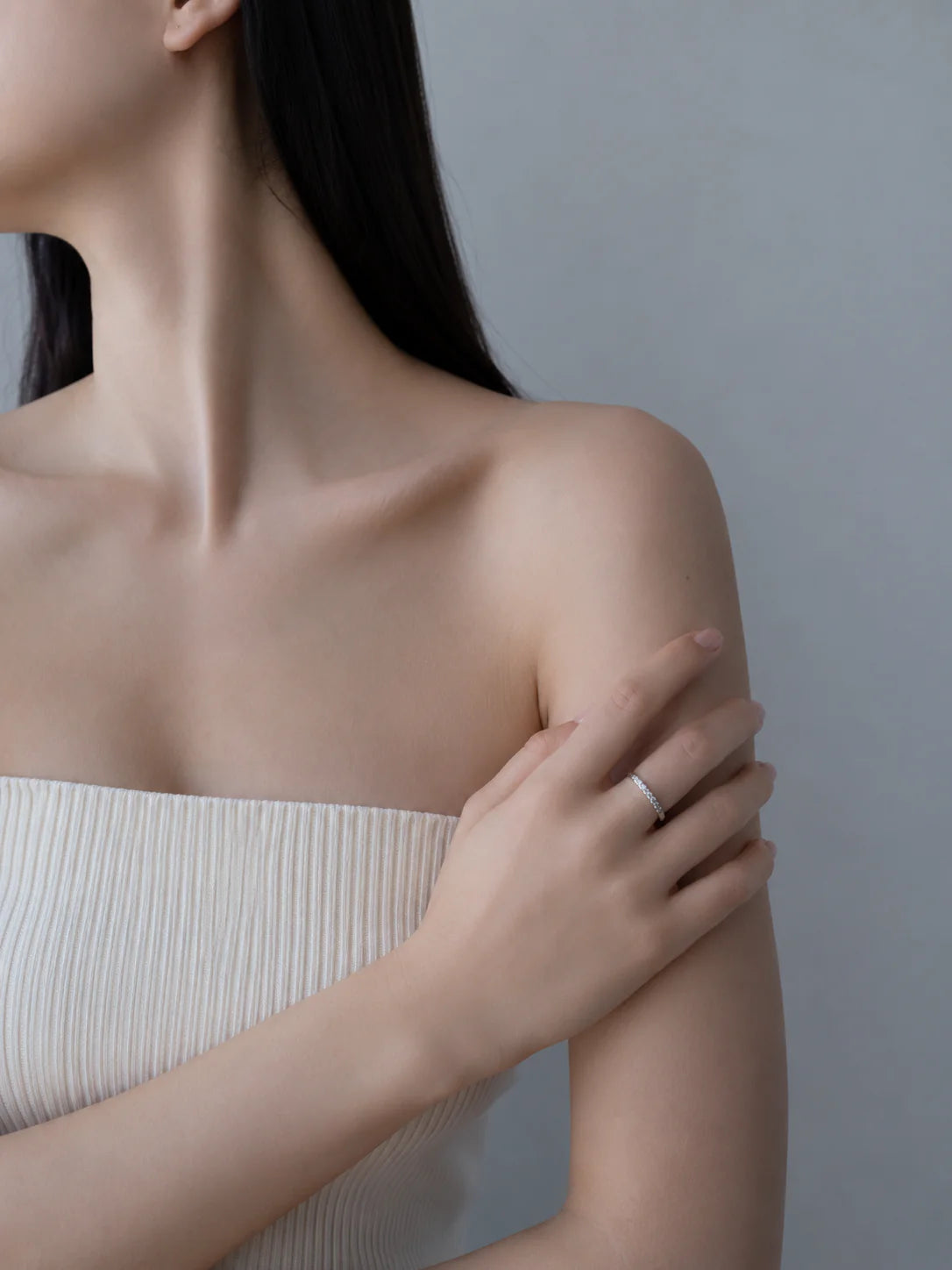 Woman wearing a white strapless top against a gray background