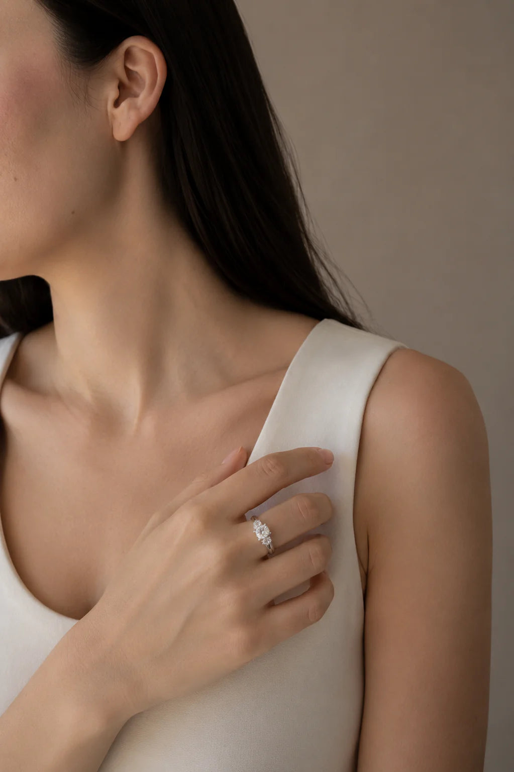 Woman wearing a diamond ring on a neutral background