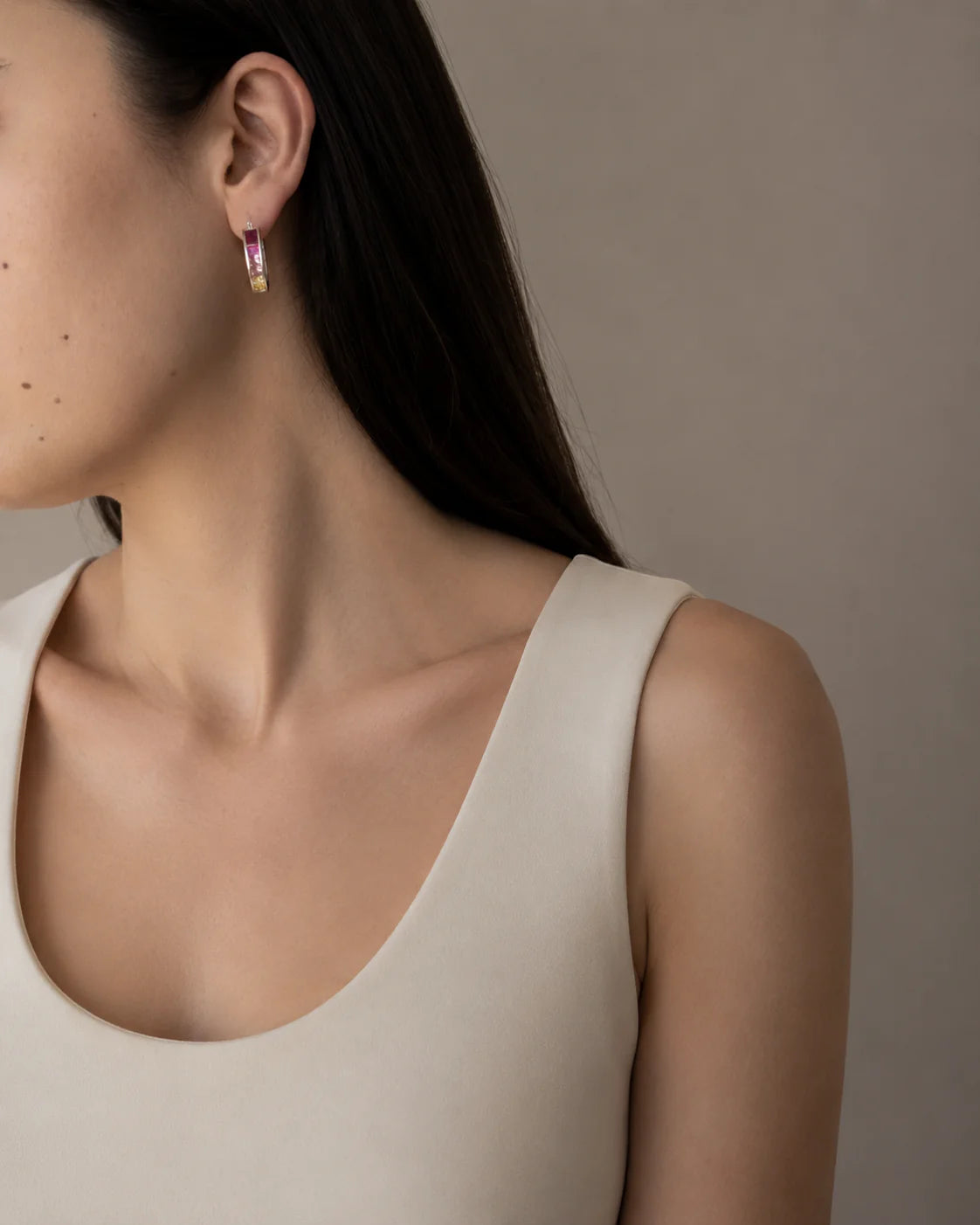 Close-up of a woman wearing pink earrings with a neutral background